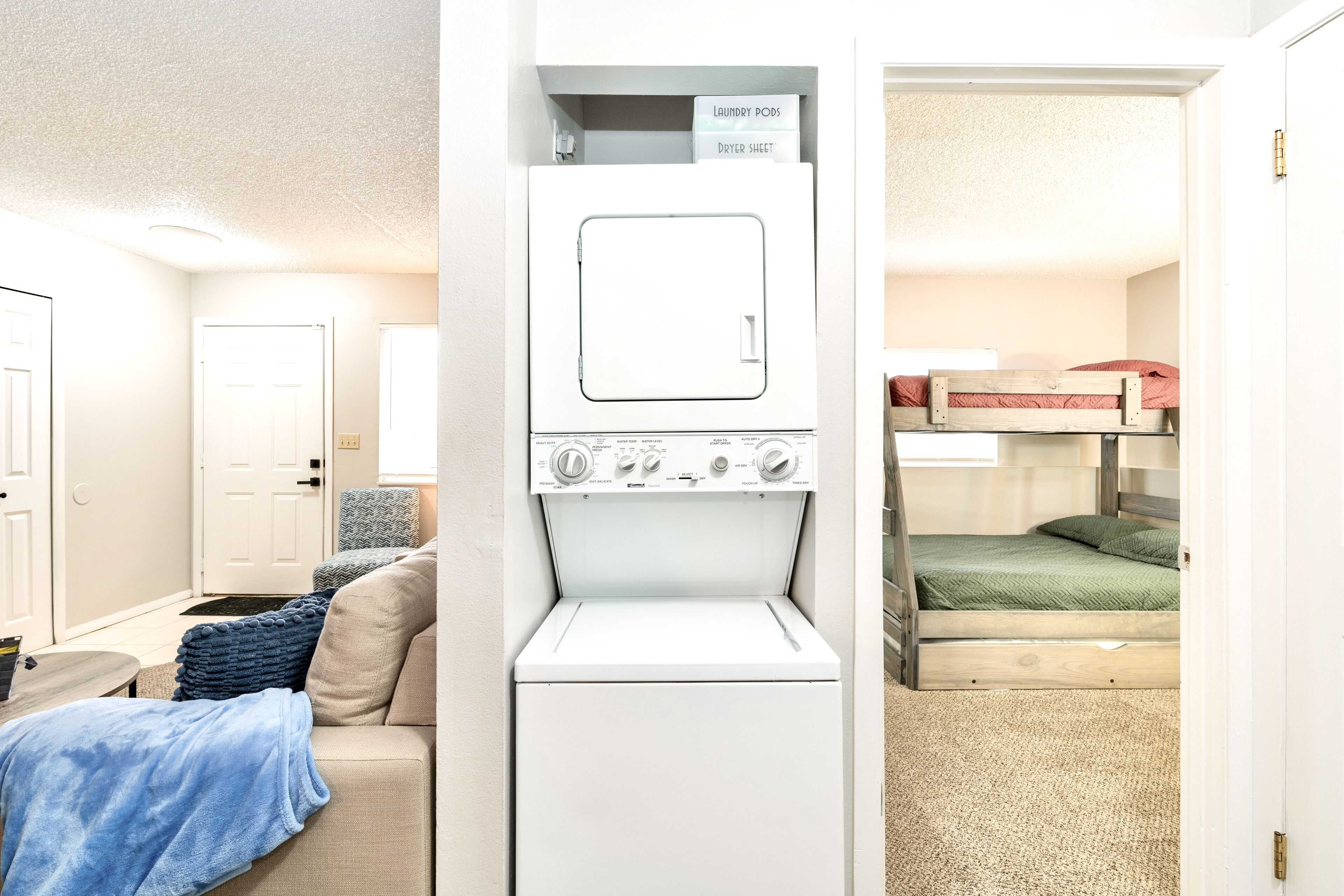 A compact room with a washing machine, a bunk bed, and a small seating area.