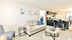 A modern living room with a sofa, coffee table, and artwork on the wall. - The Hygge apt C (Colorado Springs)