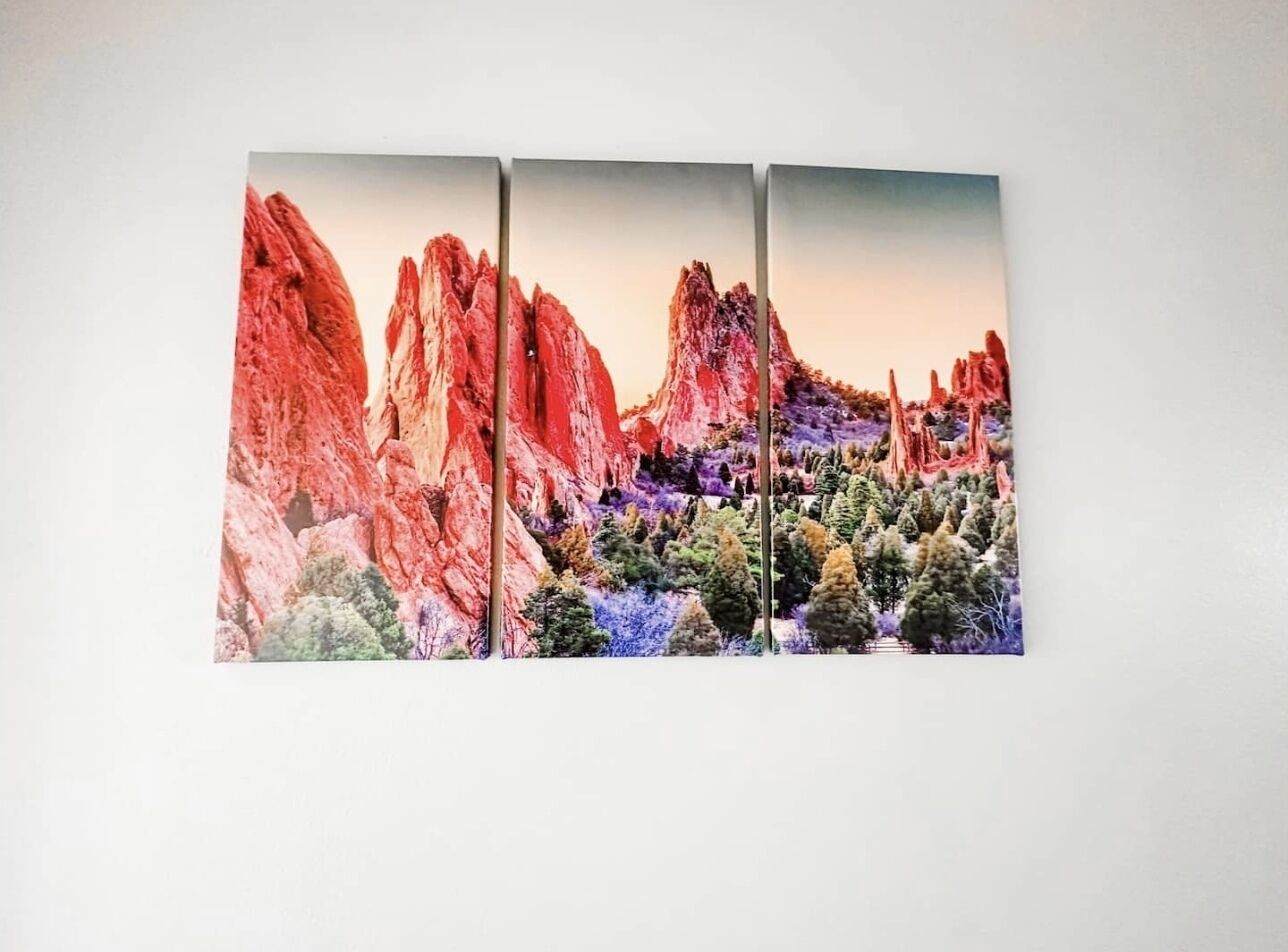 A three-panel artwork depicting a landscape with red rock formations and green trees.