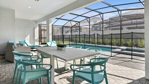 A covered outdoor area with a pool, seating, and a view of a residential building. - Grand Marvel & Star Wars Villa | Windsor Island (Davenport)