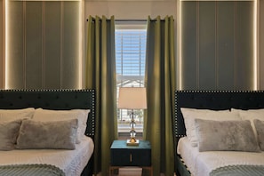 Habitación de hotel con dos camas, una mesita de noche y una ventana con cortinas.