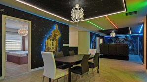 A modern interior with a dining area, a sofa, and a wall with a space-themed mural. - Grand Marvel & Star Wars Villa | Windsor Island (Davenport)