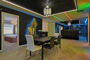 Un interior moderno con comedor, sofá y una pared con un mural de temática espacial.