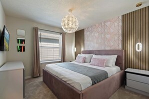 Un dormitorio moderno con una cama grande, mesitas de noche, un televisor y una decoración de pared.