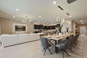 Una cocina moderna con armarios oscuros, un comedor con una mesa larga y un amplio sofá modular.