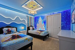 A bedroom with two beds, a nightstand, a dresser, and a wall mural.
