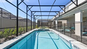 A rectangular swimming pool with a clear blue water surface, surrounded by a metal fence and a covered area with a roof structure. - Grand Marvel & Star Wars Villa | Windsor Island (Davenport)