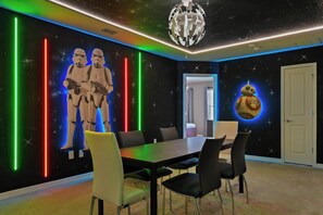 A room with a Star Wars theme, including a wall mural, neon lights, and a ceiling light fixture.