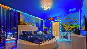 A bedroom with an aquarium wall, a round bed, and a white crib. - Grand Marvel & Star Wars Villa | Windsor Island (Davenport)