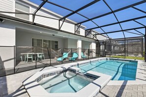 Una piscina exterior techada con sillones de descanso y un jacuzzi.