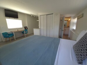 Ein Schlafzimmer mit Bett, Schreibtisch, Stuhl, Fernseher und Kleiderschrank.