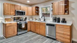 Une cuisine moderne avec des meubles en bois, des appareils électroménagers en acier inoxydable et une fenêtre qui laisse entrer la lumière naturelle.