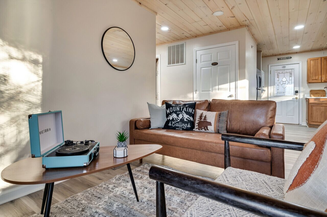 A cozy living room with a brown leather sofa, a small wooden coffee table, and a vintage blue record player.