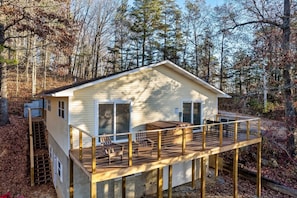 Une cabane dotée d’une terrasse, d’un espace extérieur aménagé et couvert, et d’un petit escalier menant à un niveau supérieur.