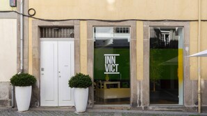 En byggnad med en vit dörr och ett stort fönster där texten "INN VICT" visas.