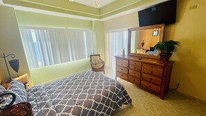 Une chambre à coucher comprenant un lit, une commode, un miroir et une fenêtre avec des stores.