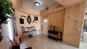 Uma sala de estar espaçosa com um conjunto de jantar, uma mesinha de apoio com velas e um espelho decorativo na parede.