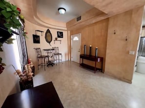 A spacious living area with a dining set, a console table with candles, and a decorative mirror on the wall.