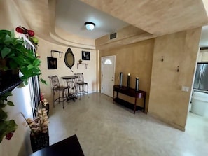 A spacious room with a dining area featuring a table and chairs, a console table with candles, and a wall-mounted mirror.