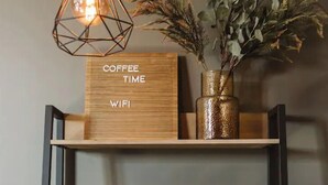 En kaffestation med en skylt som visar "KAFFE & WI-FI", en kaffebryggare, koppar och en prydnadsväxt.