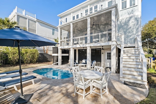 A two-story house with a pool, outdoor seating, and a staircase.