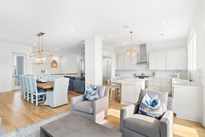 A modern kitchen with white cabinets, a central island, and pendant lighting. - Modern Beach Home w/Private Pool, 3 Master Suites & Short Walk to Beach! (Isle Of Palms)
