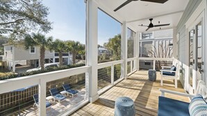 Um terraço coberto ao ar livre com cadeiras de estar azuis e um ventilador de teto.