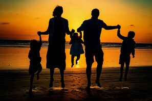 A silhouette of a family against a sunset on a beach.