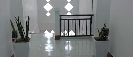 Un hall d’entrée spacieux aux murs blancs, doté d’un sol carrelé et agrémenté de deux plantes en pot.