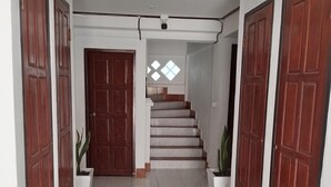A hallway with a tiled floor, wooden doors, and a staircase leading to an upper level. - Ban Saylomleng Residence (Vientiane)