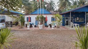 A building with a blue roof, surrounded by palm trees and a gravel courtyard. - Ban Saylomleng Residence (Vientiane)