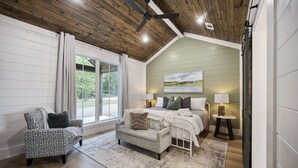 A bedroom with a bed, a chair, a small table, and a ceiling fan.
