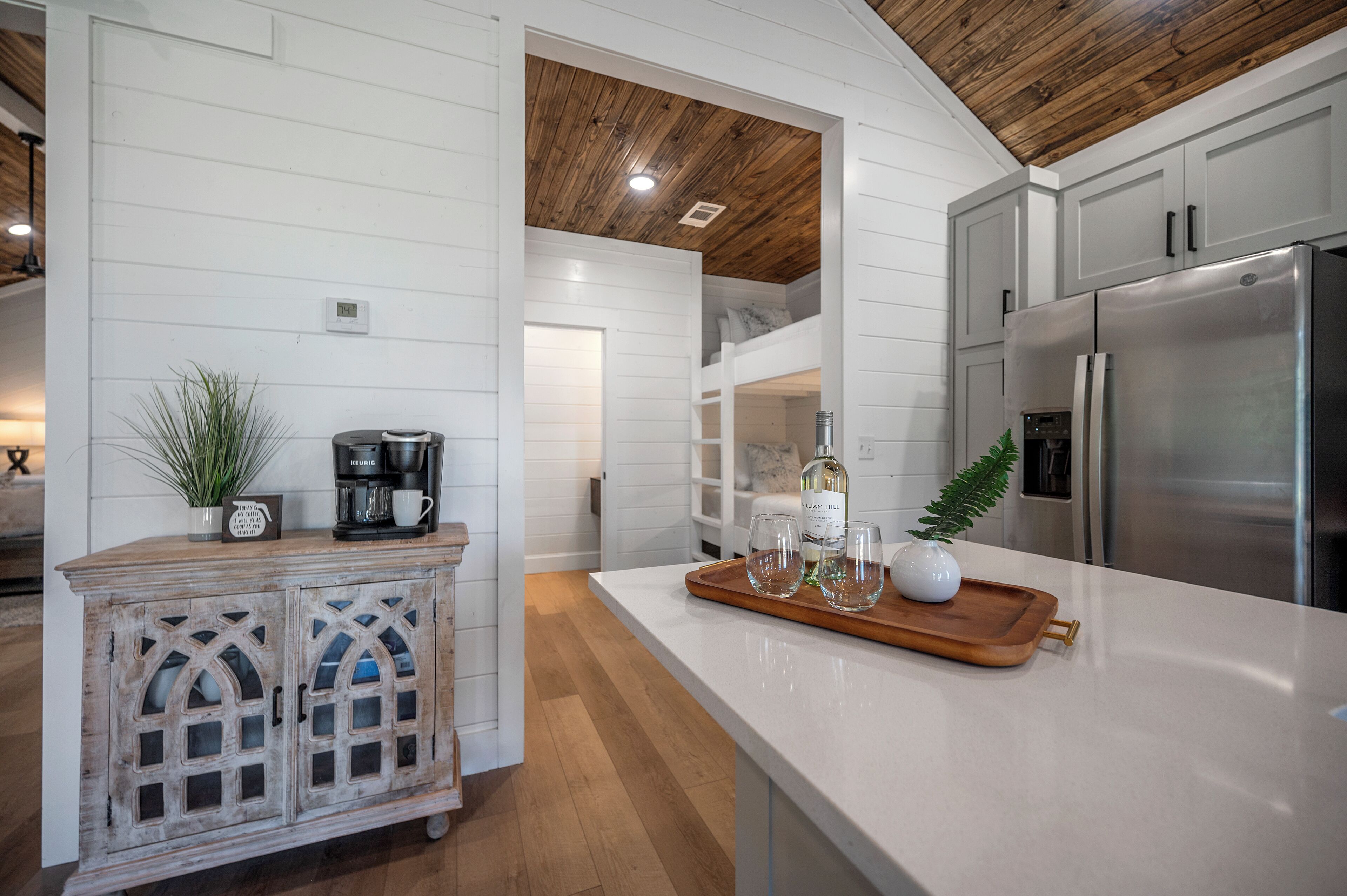 A kitchen with white cabinetry, a wooden ceiling, and a stainless steel refrigerator.