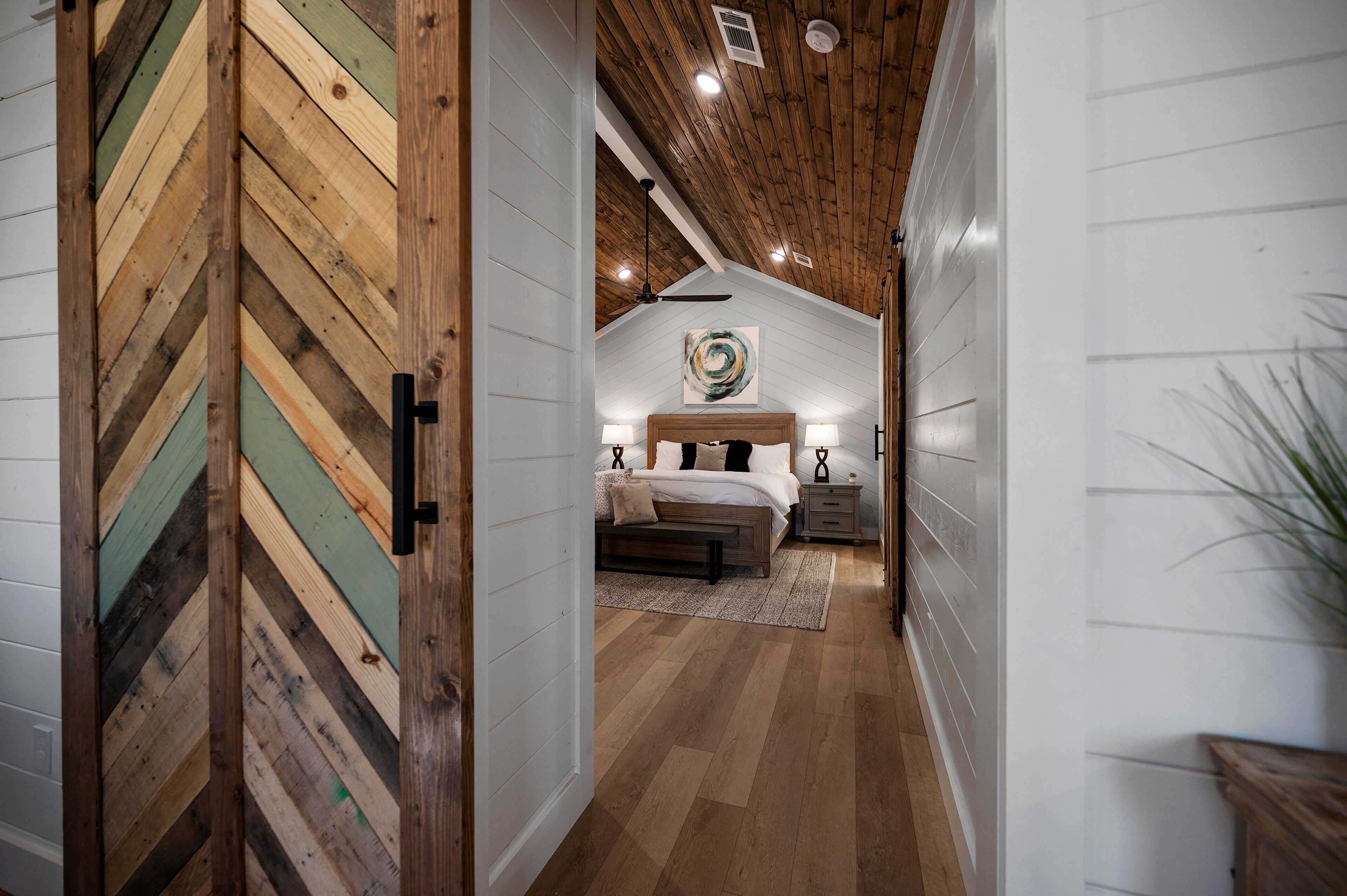 Een slaapkamer met een houten plafond, een bed, nachtkastjes en een plafondventilator.