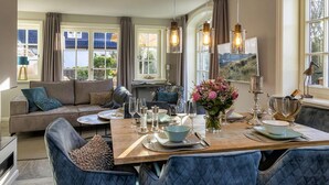 Un coin repas avec une table en bois dressée pour quatre personnes, entourée de chaises recouvertes d’un tissu bleu.