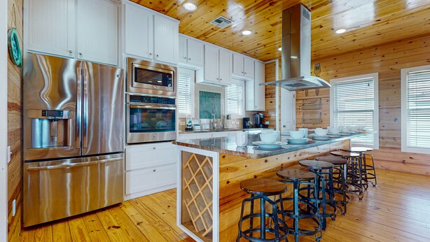Una cocina moderna con electrodomésticos de acero inoxidable, suelo de madera e una isla central con taburetes de bar.