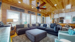 Una sala de estar acogedora con un sofá modular, un reposapiés y un ventilador de techo.