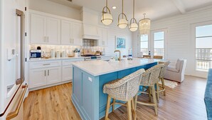 A spacious kitchen with white cabinets, a blue island, and a chandelier. - Private Heated Pool, Golf Cart Included, Pet Friendly (Port Aransas)
