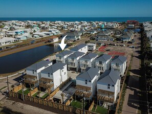 A coastal residential area with modern houses, a marina, and a clear view of the ocean. - Private Heated Pool, Golf Cart Included, Pet Friendly (Port Aransas)