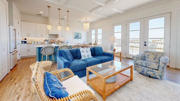 A spacious living area with a blue sofa, wicker chairs, and a glass coffee table. - Private Heated Pool, Golf Cart Included, Pet Friendly (Port Aransas)