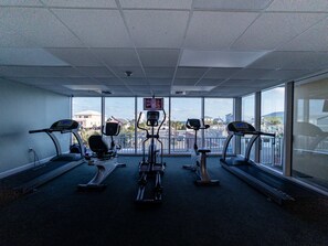 A gym with treadmills, ellipticals, and a mirrored wall.