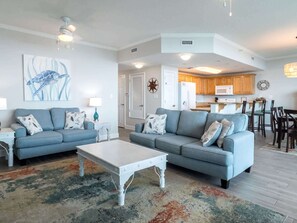 A spacious living room with two sofas, a coffee table, and a kitchen in the background. - Sanibel 406 by ALBVR - Beautiful updates with views that are simply amazing! (Gulf Shores)