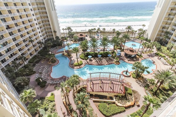 Relax by the resort's central pools, surrounded by sun loungers and umbrellas, with ocean views and palm trees nearby.