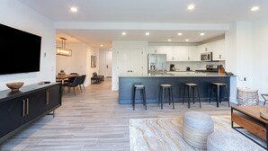A modern kitchen with a central island, bar stools, and a dining area with a TV and seating. - Bear Creek Lodge 207a Condo by Alpine Lodging Telluride (Telluride)