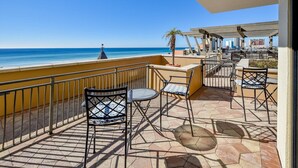 Une terrasse avec des sièges extérieurs, une vue sur la mer et un palmier.