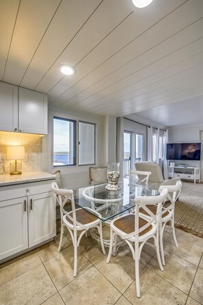 Relax in a spacious living area with a round table and comfortable seating for four, featuring a flat-screen TV and large windows.