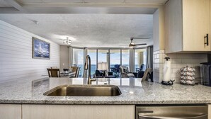 A modern kitchen with a large island, stainless steel appliances, and a view to the outside. - Long Beach Tower 3, #1303 - Completely Renovated 2 Bedroom . 2 Condo by RedAwning (Panama City Beach)