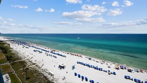 A beach with rows of umbrellas and beach chairs, a pier extending into the water, and a clear sky. - Long Beach Tower 3, #1303 - Completely Renovated 2 Bedroom . 2 Condo by RedAwning (Panama City Beach)