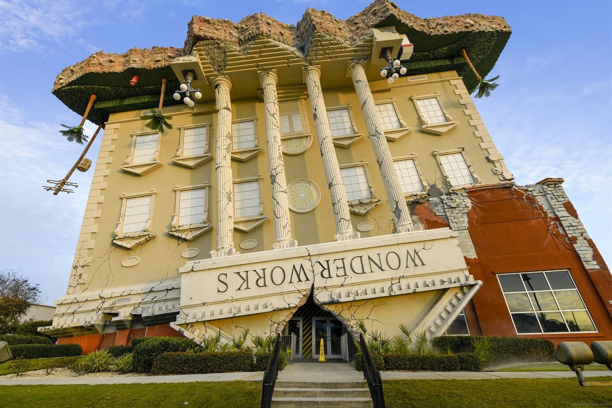 Um edifício com um grande letreiro que diz "NOBLE ROOMS". Apresenta colunas clássicas, uma entrada central com degraus e um design de telhado único.