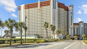 A multi-story hotel with a central tower, balconies, and a parking garage. - Shores of Panama 1418 - 2 Bedroom+Bunkroom ! Updated with a View! Free Fun! 2 Condo by RedAwning (Panama City Beach)